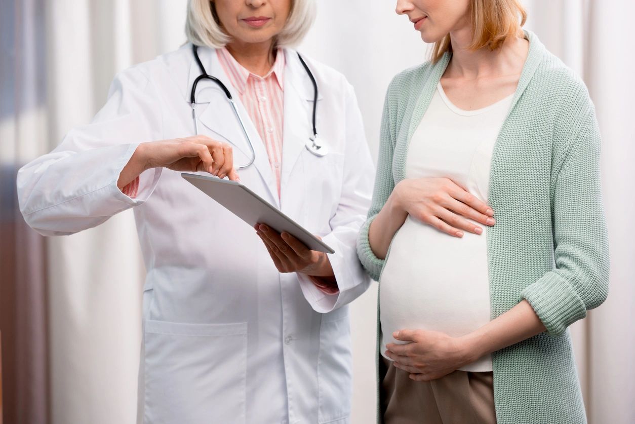pregnant woman talking to a doctor while looking at a clipboard