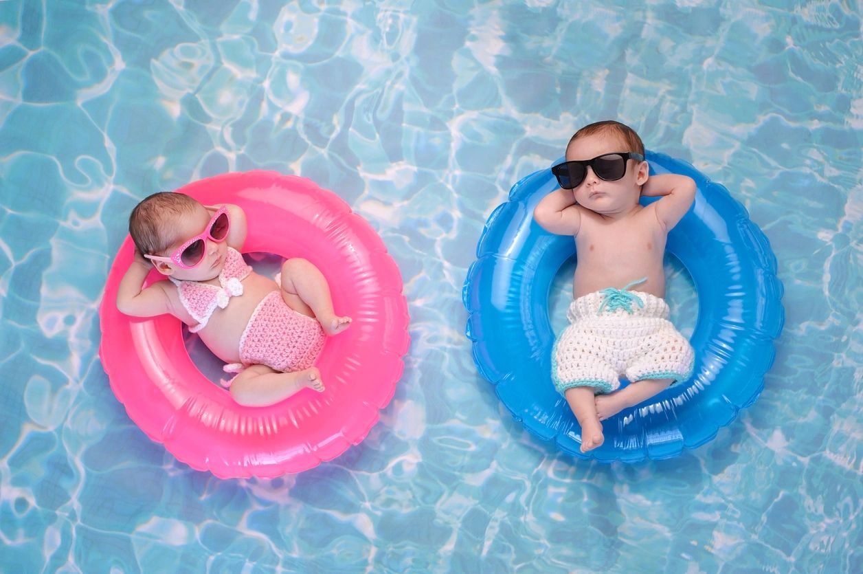 Two babies in pool using pool floats